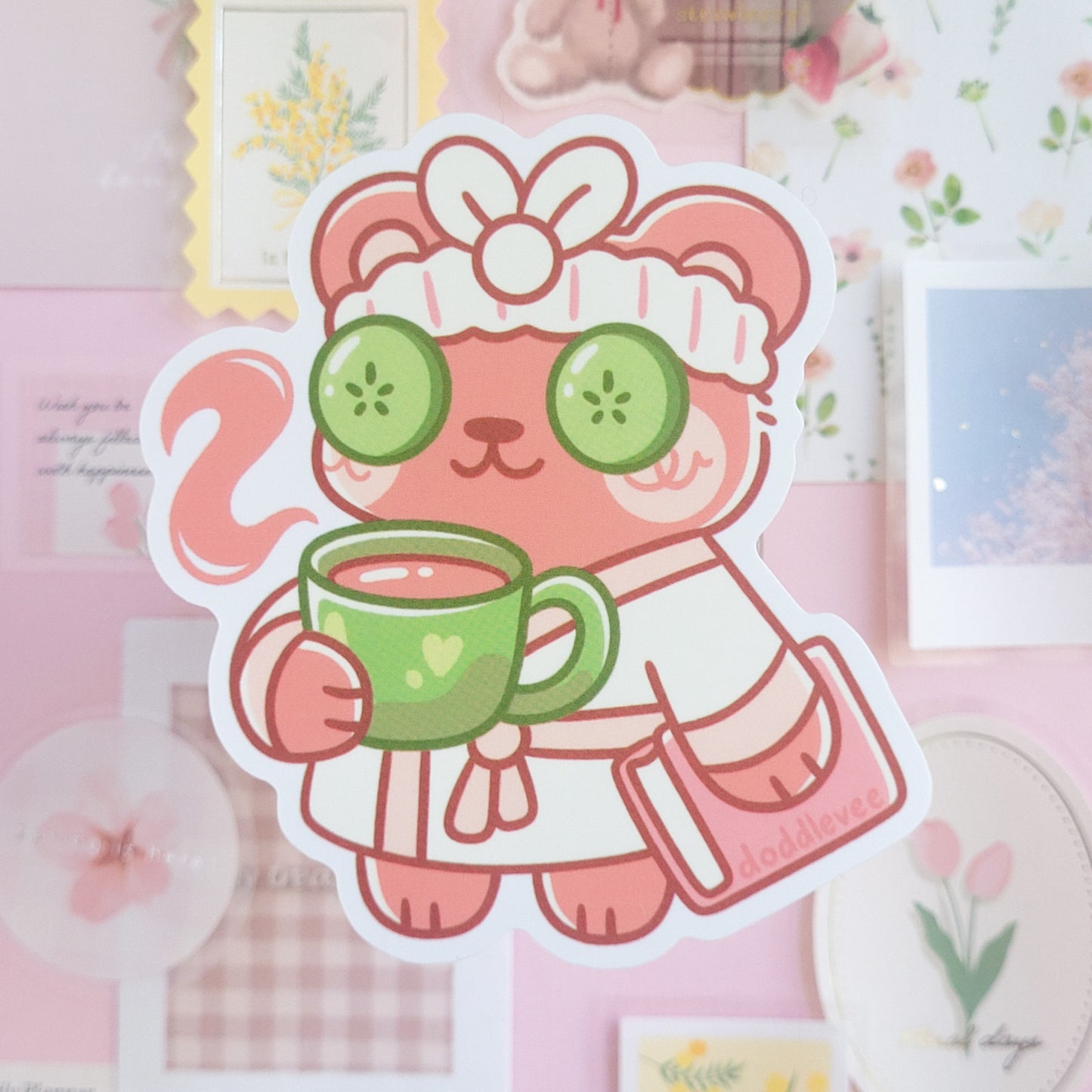 Sticker of pink bear with cucumbers on eyes and style is as if they are about to have a spa day.