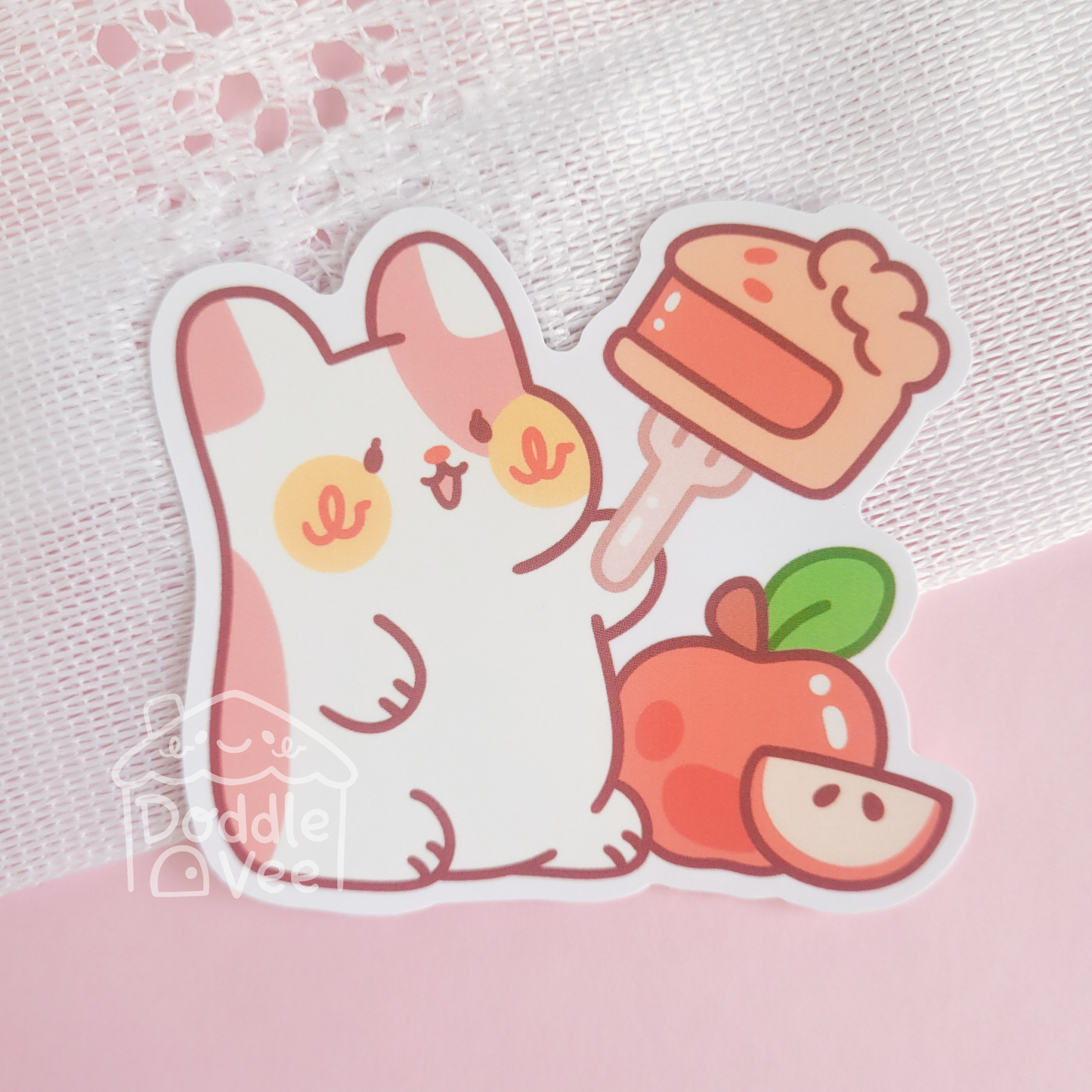 Cartoon cat holding a cupcake with an apple on a pink background