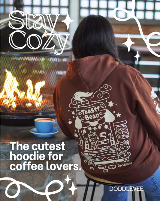 Person wearing a brown hoodie with a coffee-themed design, sitting by a fire.