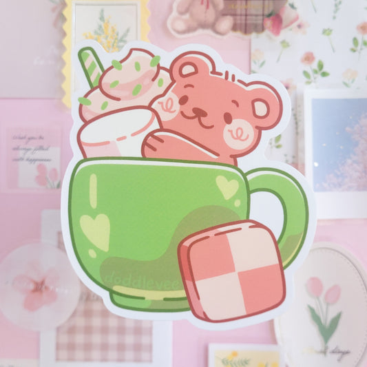 Sticker of a bear in a green mug with a pink heart on a pink background