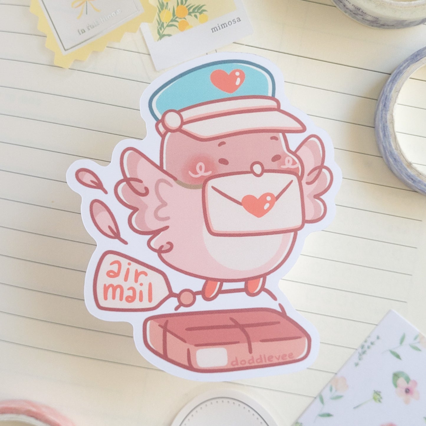 Sticker of pink pidgeon with a letter in its mouth carring a package that says air mail