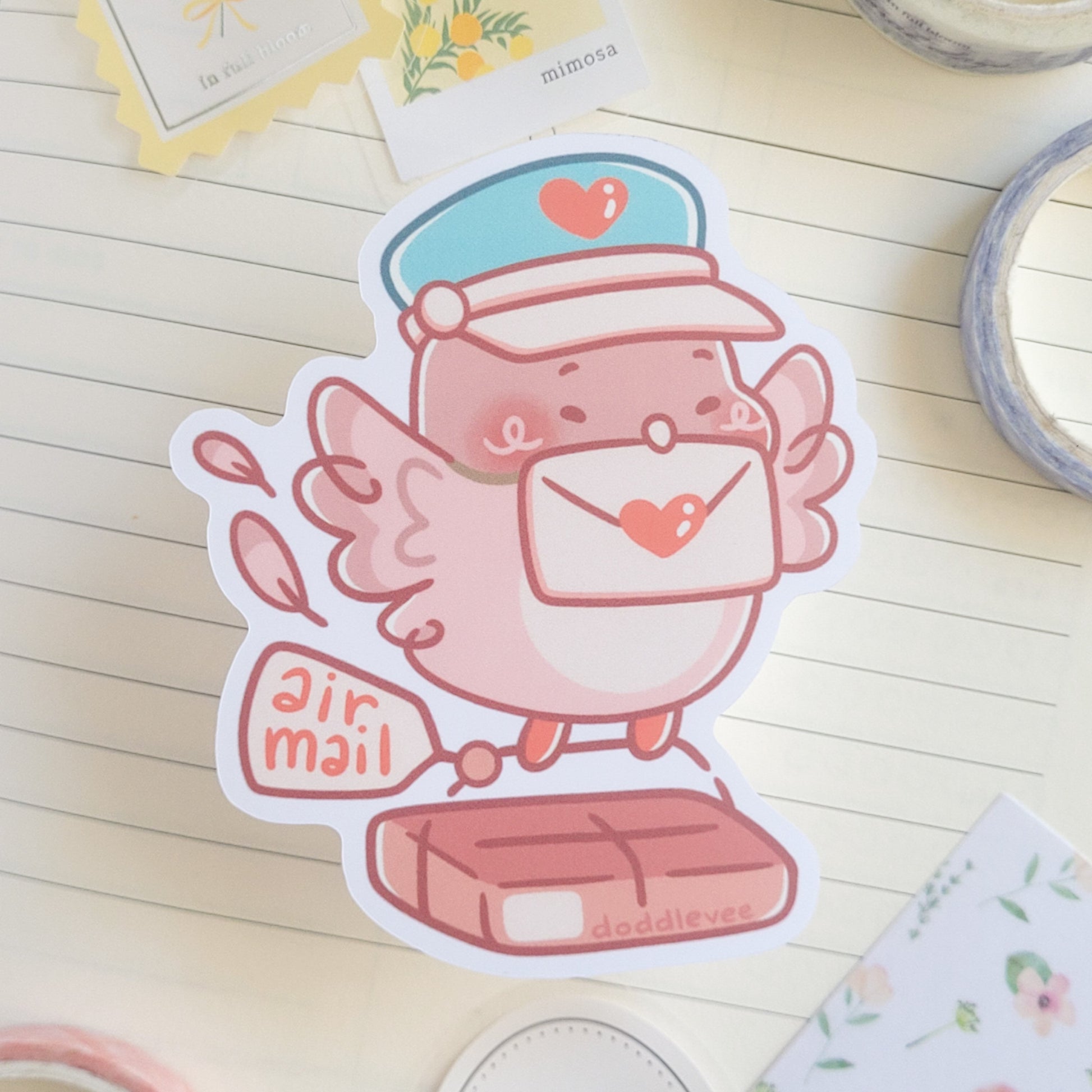 Sticker of pink pidgeon with a letter in its mouth carring a package that says air mail