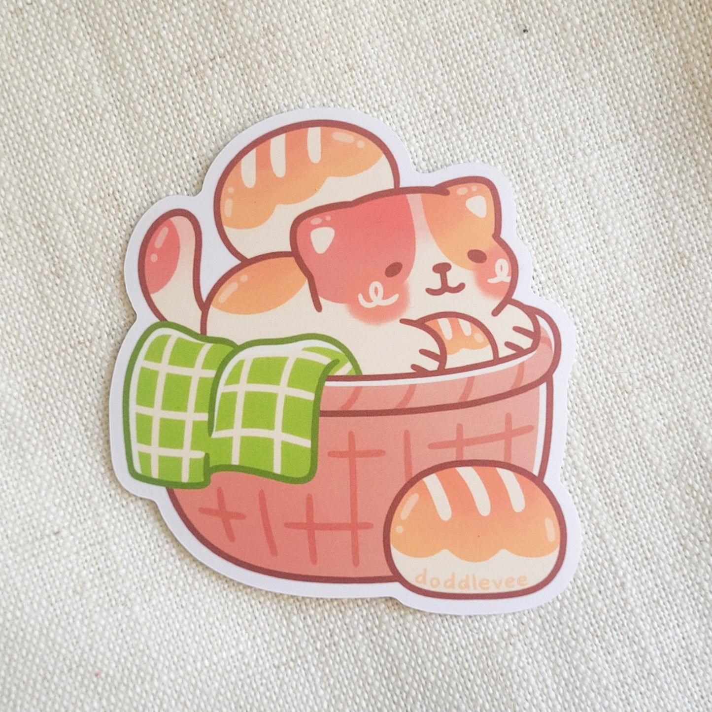 Sticker with a cat sitting in a basket holding loaves of bread