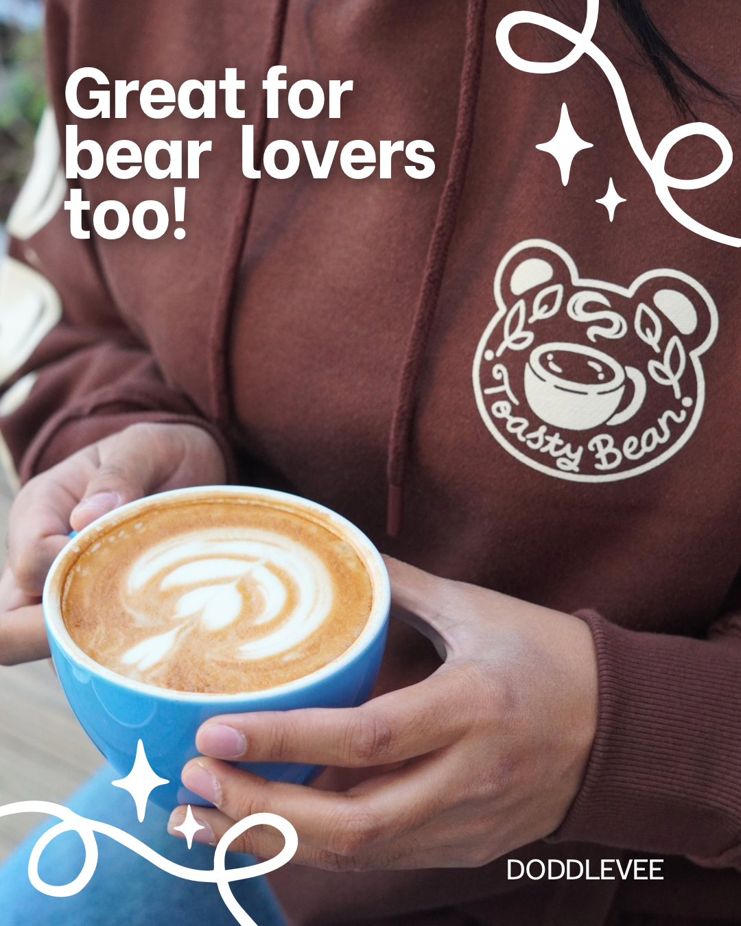 Person holding a blue cup of coffee with a brown hoodie featuring a bear logo, text 'Great for bear lovers too!' and brand name 'Doddlevée'.