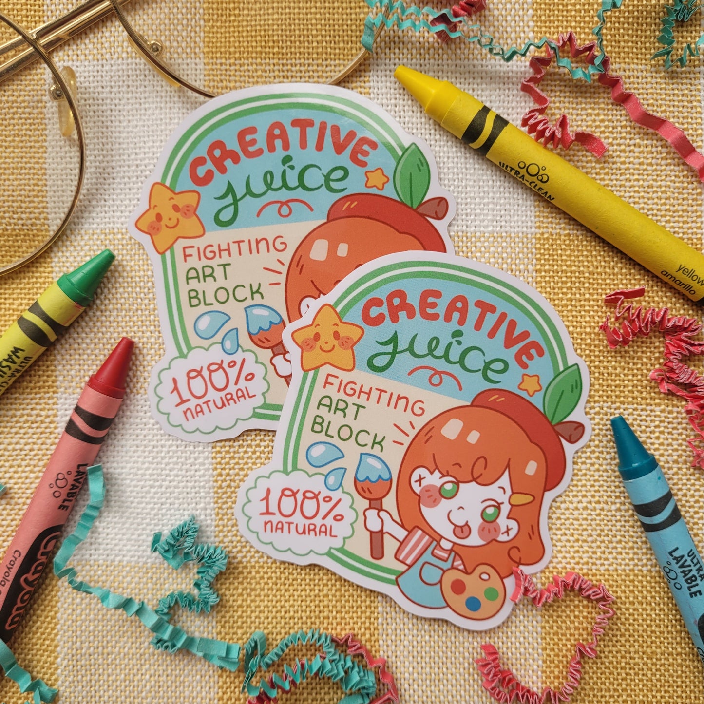 Sticker witht he words creative juce, fighting art block on it. Shows a orange haired girl holding a paint brush