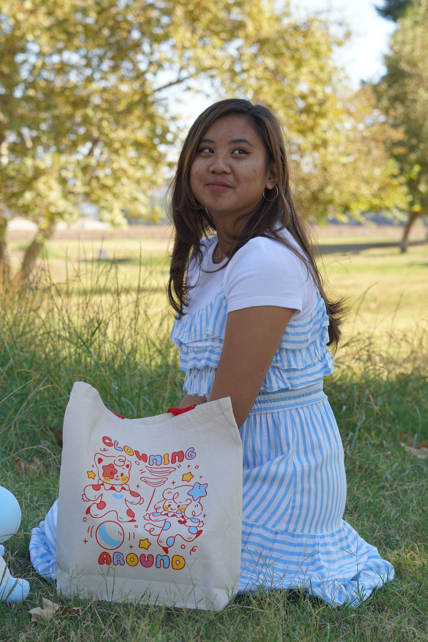 Woman holding a tote bag with colorful designs outdoors