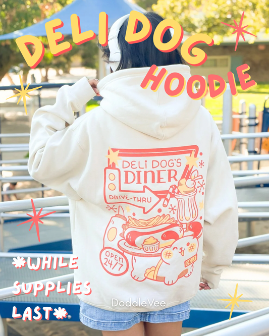 Person wearing a white hoodie with 'Deli Dog Diner' design, standing outdoors.