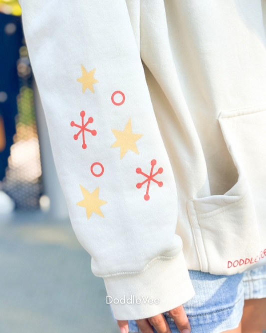 Close-up of a white sweatshirt with colorful star patterns on a blurred outdoor background.