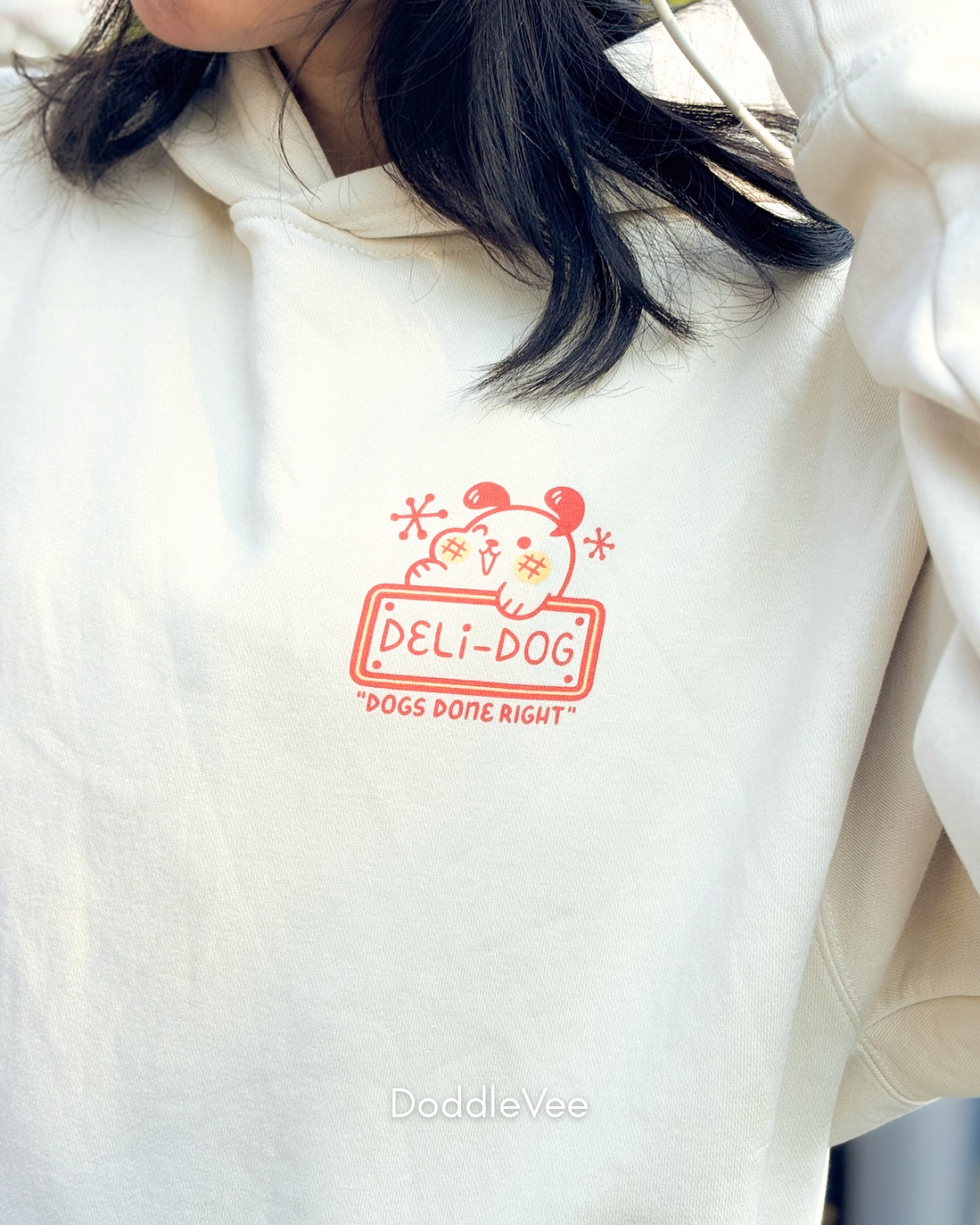 White hoodie with red 'DELI-DOG' logo worn by a person