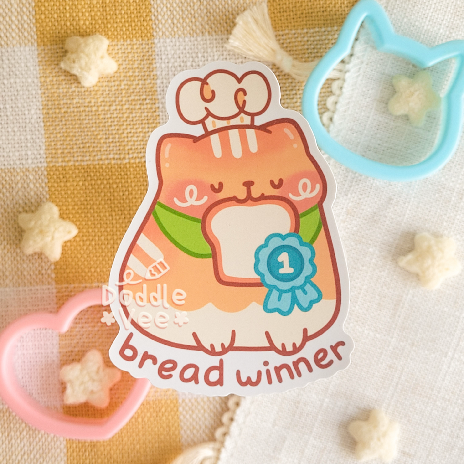 Sticker of orange cat with bread in its mouth. Text bread winner below it.