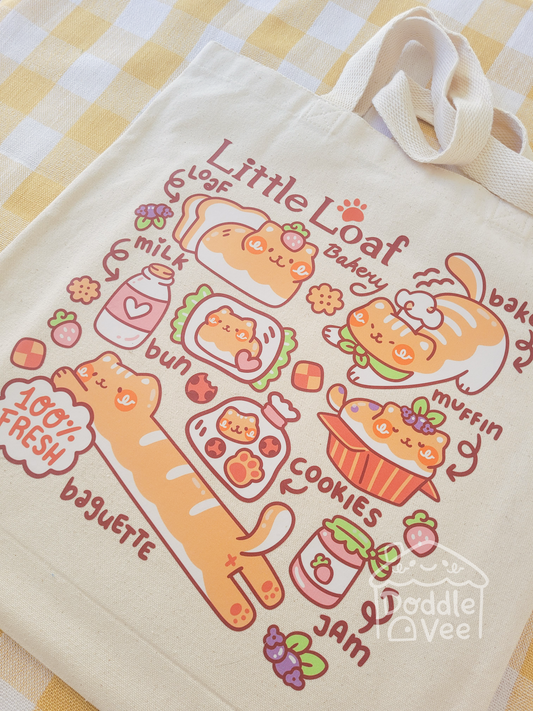 Beige tote bag with cute bakery-themed illustrations and text on a checkered background