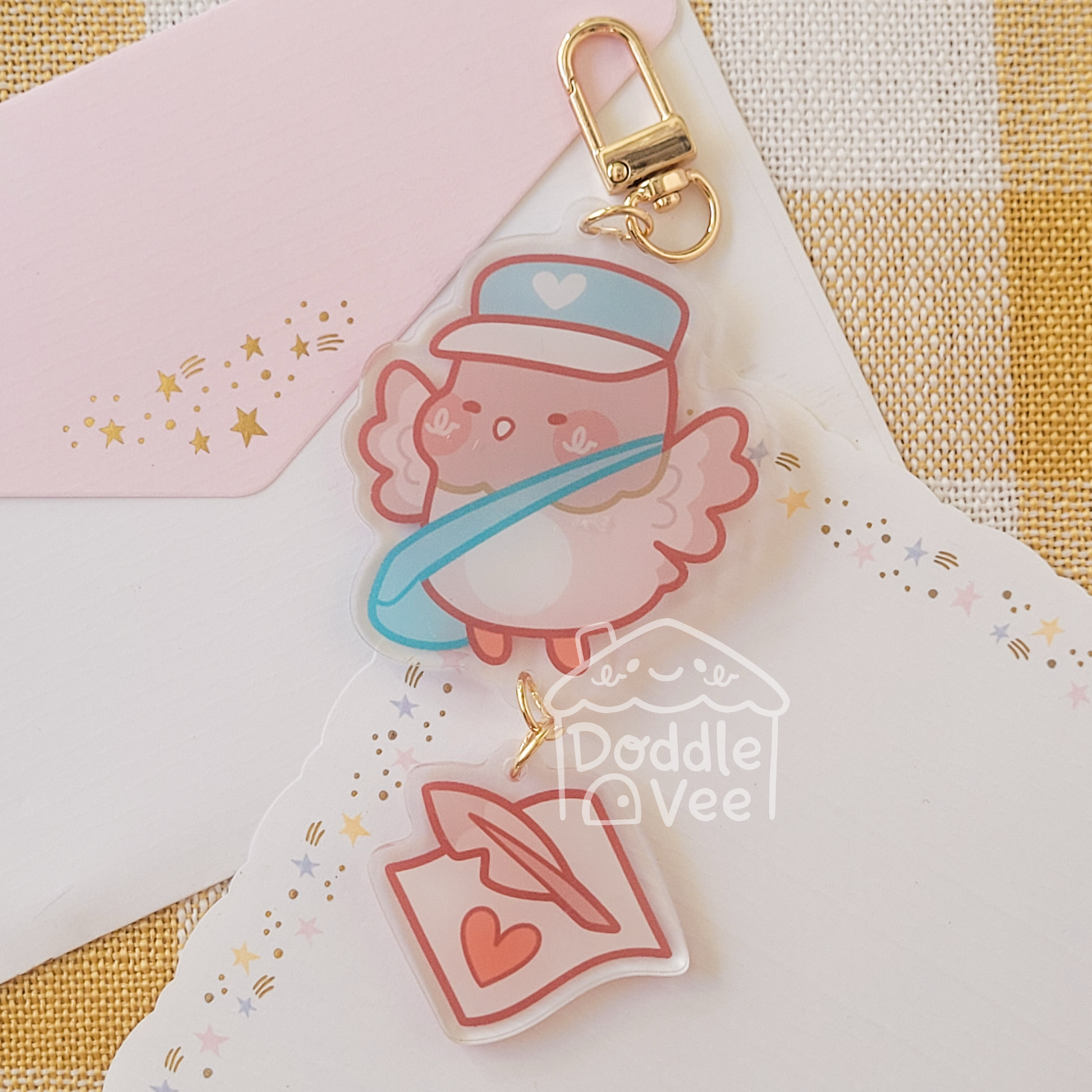 Link keychain of pink pidgeon. Second link keychain is a note and quill.