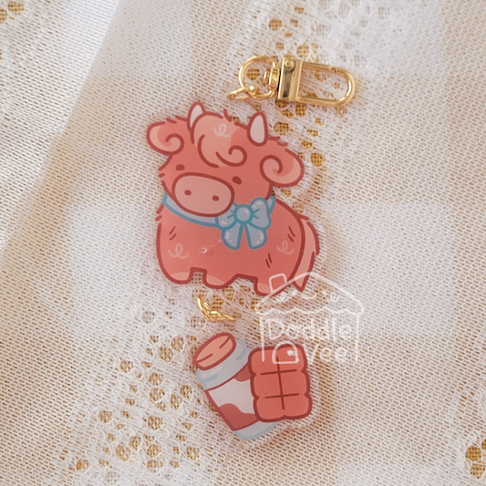 Link keychain of brown highland cow, second link keychain is a bottle of milk and a chocolate bar
