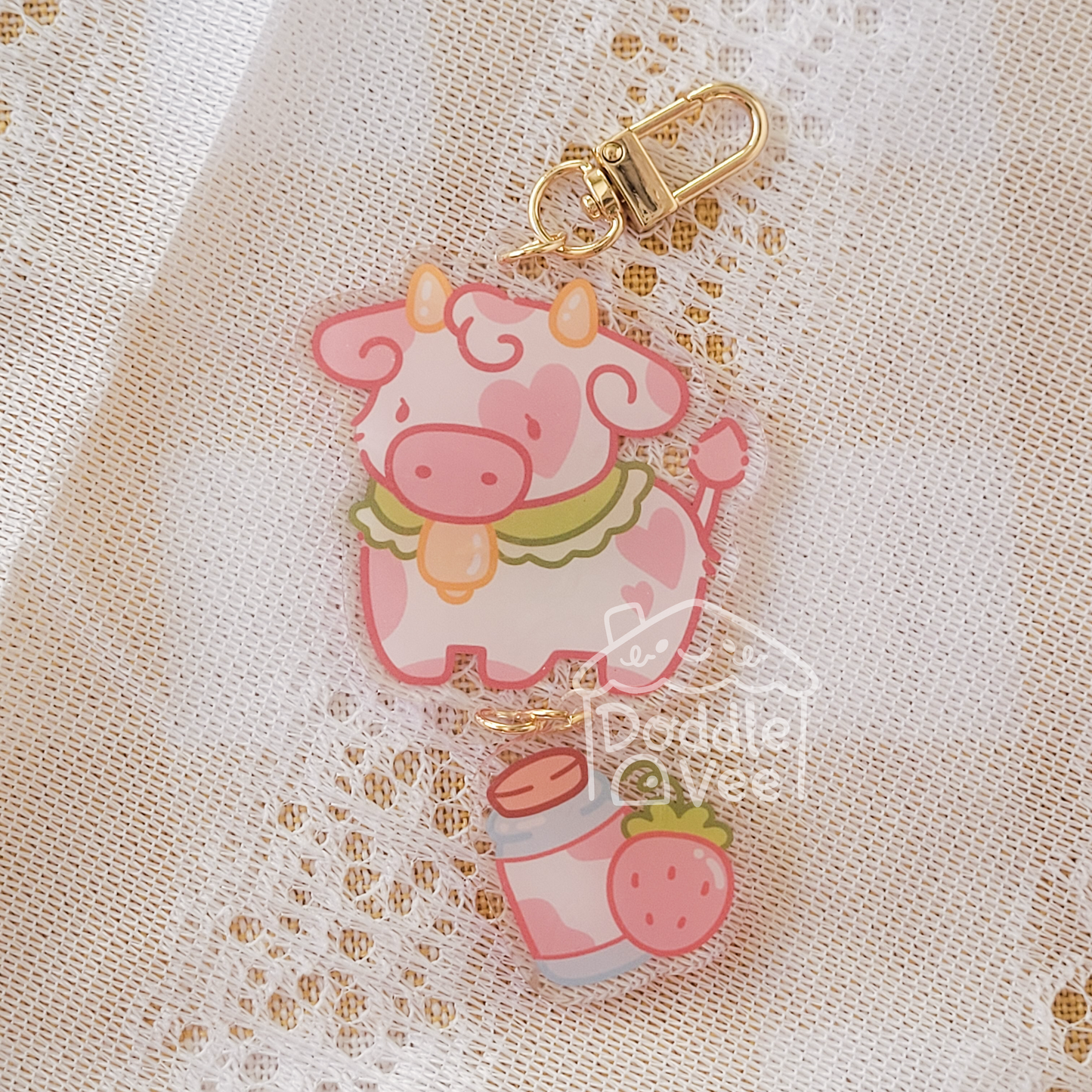 Pink cow keychain with strawberry on a beige lace background