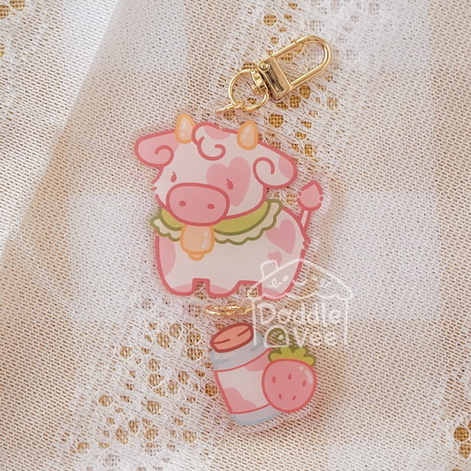 Pink cow keychain with strawberry on a beige lace background