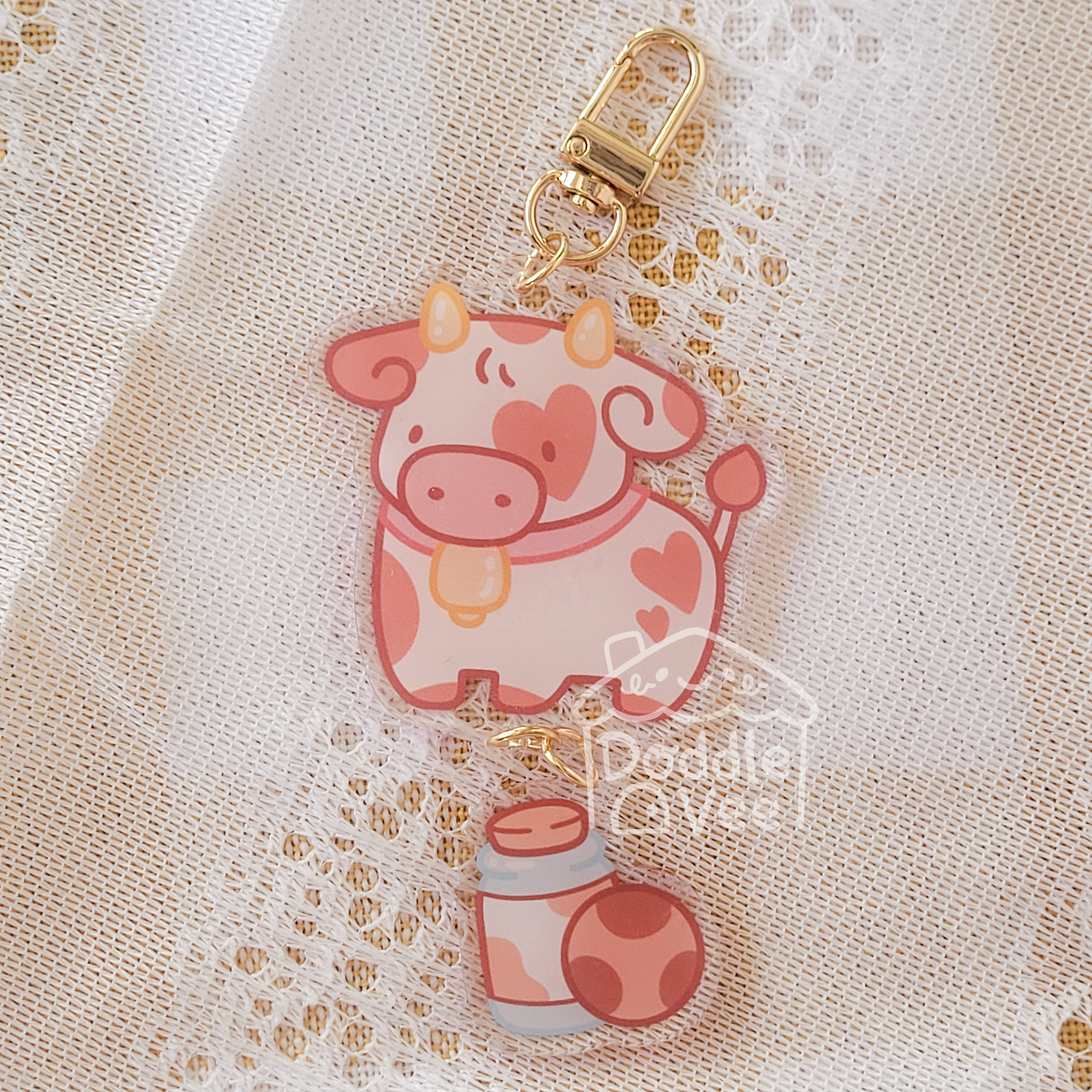 Link keychain of pink cow and second link keychain is a glass of milk and cookie
