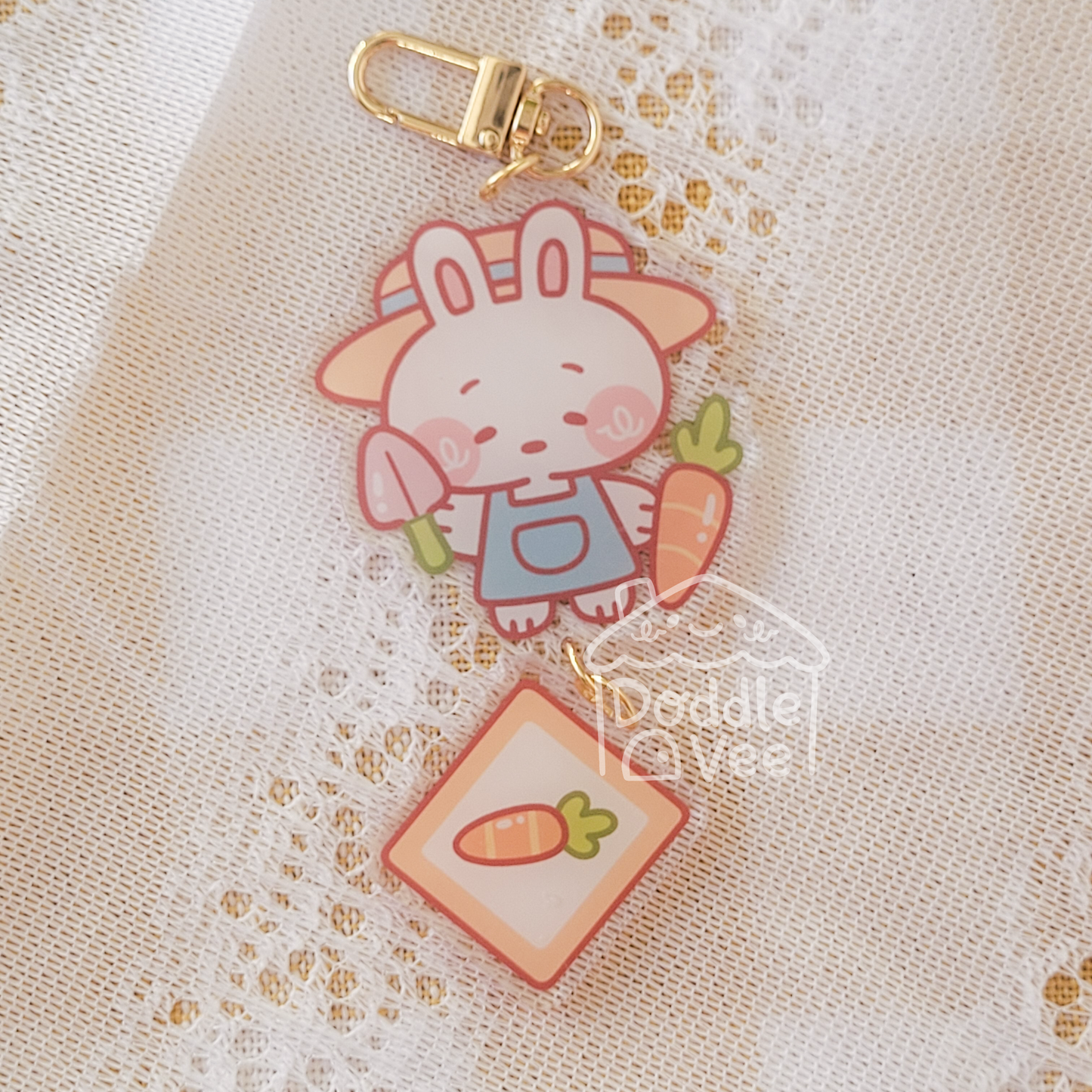 Link keychain of bunny holding carrot and shovel. Second link keychain is a picutre of a carrot