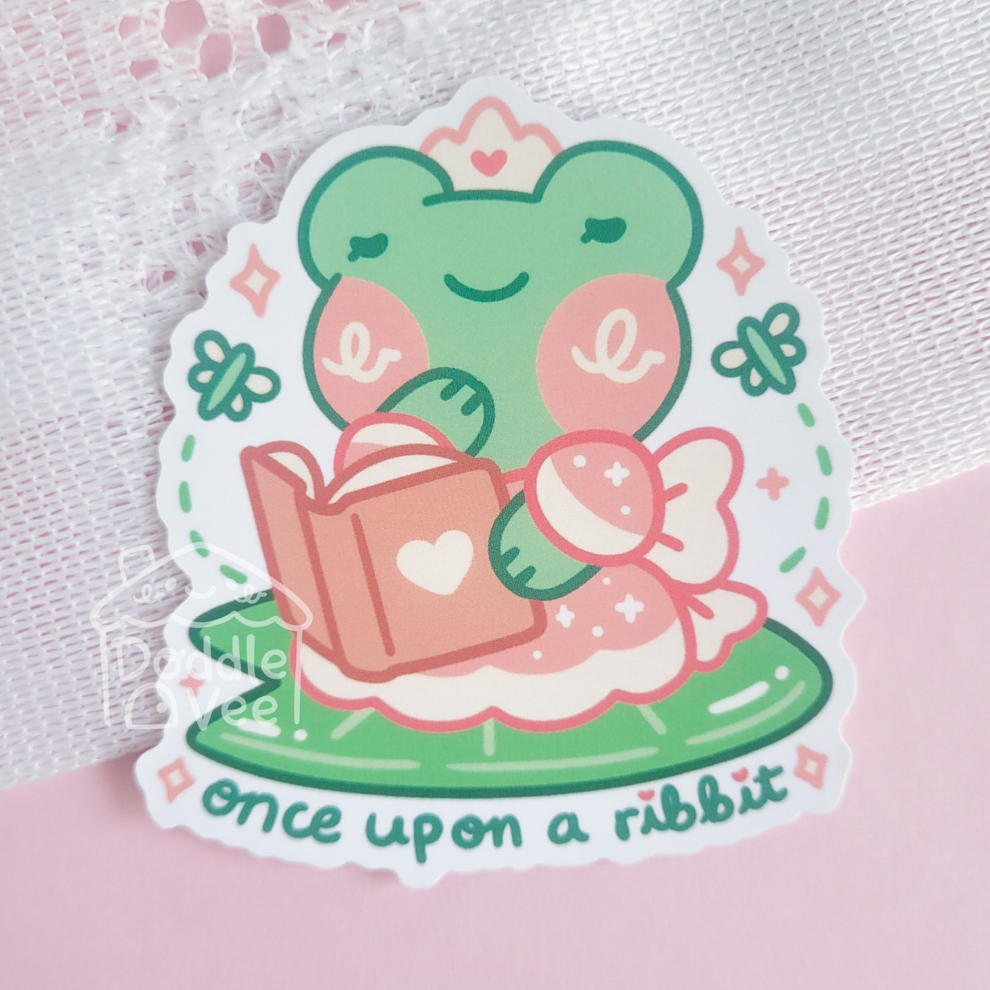 Sticker of a green rabbit reading a book with 'once upon a rabbit' text on a pink background.