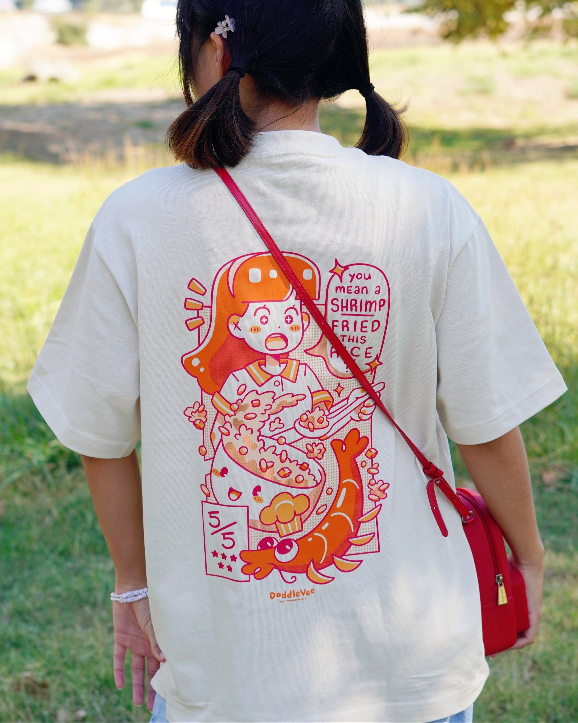 Person wearing a white t-shirt with a colorful graphic design outdoors.