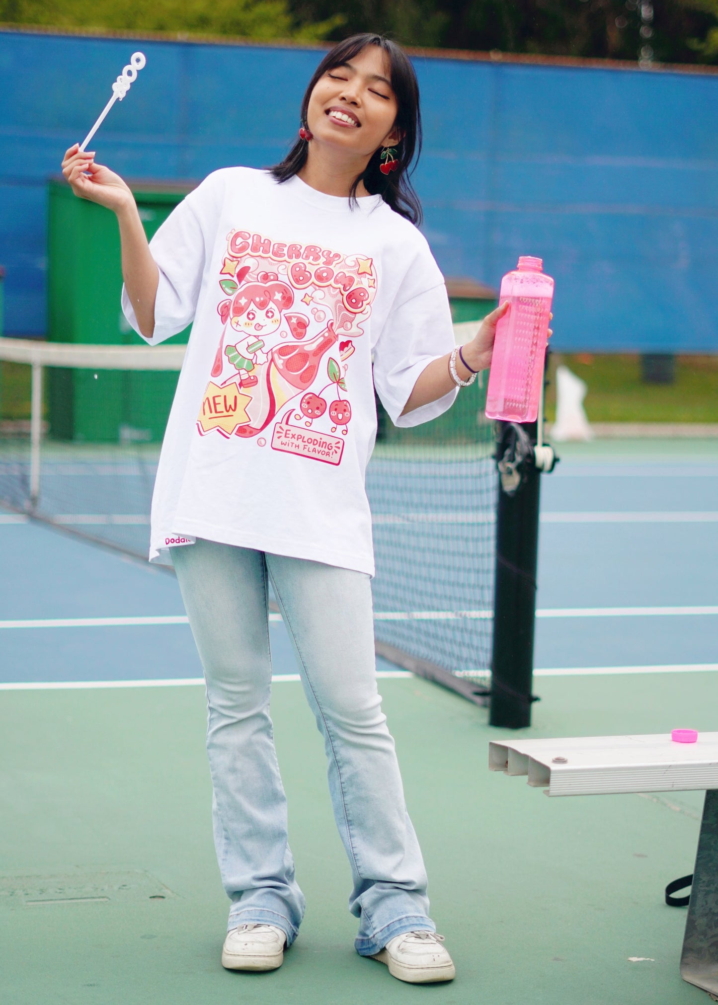 Person standing on a tennis court holding a pink water bottle