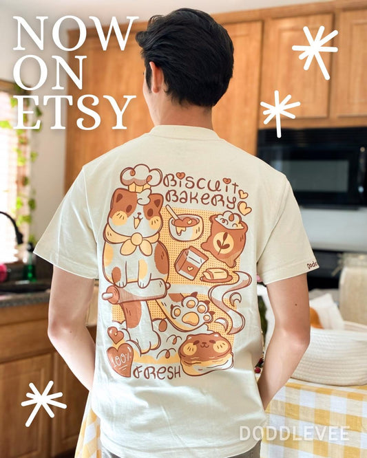 Person wearing a t-shirt with a cat and bakery design in a kitchen setting, with 'Now on Etsy' text overlay.